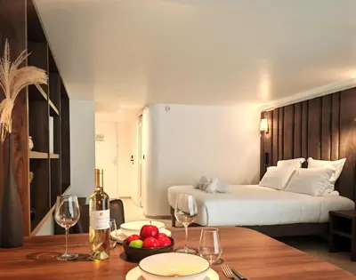 a hotel room with a bed and a table with wine glasses at Hôtel & Appartements Monsigny in Nice