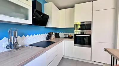 a kitchen with white cabinets and a blue wall at L'Éclat d'Azur in Nice