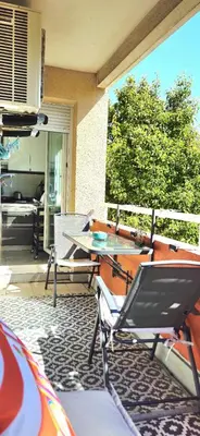 a patio with a table and chairs on a porch at Spacious 3 room close to tram and amenities in Nice