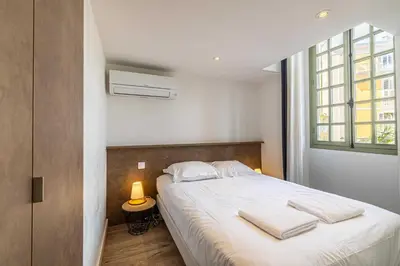 a bedroom with a bed with white sheets and a window at Residence Garibaldi - Nice in Nice