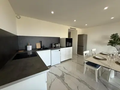 a kitchen with white cabinets and a table with chairs at Sea View, Modern Apartment and Terrace in Nice