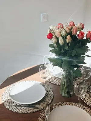 a table with white plates and a vase of flowers at Nice Center - Spacious Luxury Apartment with Air Conditioning in Nice