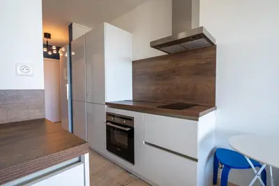 a kitchen with white cabinets and a table with a blue stool at Azzuro - Mare e Terrazza in Nice