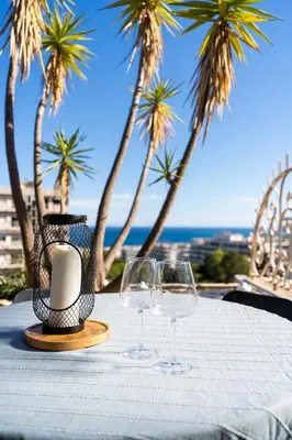 two wine glasses sitting on a table with palm trees at Azzuro - Mare e Terrazza in Nice