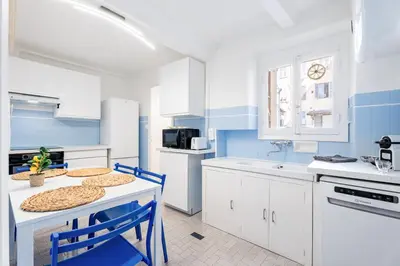 a kitchen with blue and white cabinets and a table and chairs at Nice Renting - 6C FRANCE - Chic Stay Pedestrian Zone Sea Massena in Nice