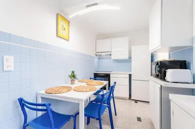 a kitchen with a white table and blue chairs at Nice Renting - 6C FRANCE - Chic Stay Pedestrian Zone Sea Massena in Nice
