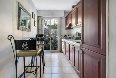 a kitchen with wooden cabinets and a table and chairs at Apartement ensoleillé vue mer in Villefranche-sur-Mer