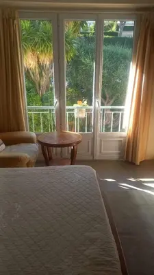 a bedroom with a bed and a table and a window at Apartement ensoleillé vue mer in Villefranche-sur-Mer