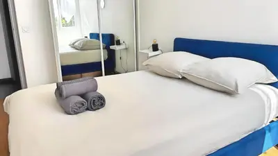 a white bed with a blue headboard and a mirror at Appartement confortable avec balcon - Proche Gare Riquier SNCF in Nice