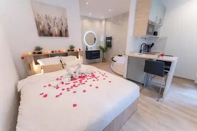 a bedroom with a bed with red rose petals on it at Nice Port studio avec grande baignoire in Nice