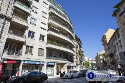 a tall white building with cars parked on a street at Apartment neighborhood Liberation in Nice
