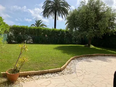 a garden with a palm tree and a lawn at Beautiful 3 bedroom apartment with nice garden in Nice