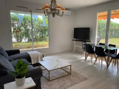 a living room with a couch and a table and a tv at Beautiful 3 bedroom apartment with nice garden in Nice