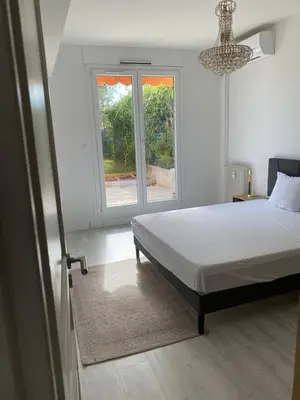 a white bedroom with a bed and a window at Beautiful 3 bedroom apartment with nice garden in Nice