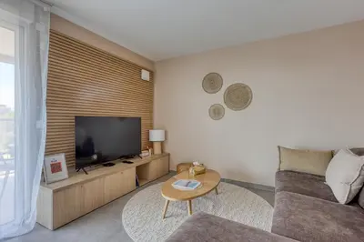 a living room with a couch and a flat screen tv at Les Vagues du 5e 4 personnes , 2 chambres , clim , wifi , Cap3000 à pied , parking in Saint-Laurent-du-Var