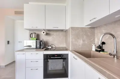 a kitchen with white cabinets and a sink at Les Vagues du 5e 4 personnes , 2 chambres , clim , wifi , Cap3000 à pied , parking in Saint-Laurent-du-Var