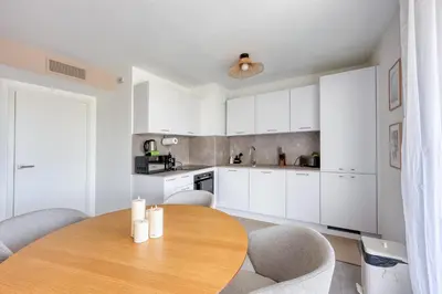 a kitchen with a wooden table and chairs at Les Vagues du 5e 4 personnes , 2 chambres , clim , wifi , Cap3000 à pied , parking in Saint-Laurent-du-Var