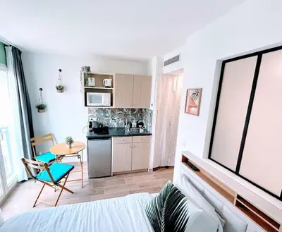 a room with a bed and a kitchen with a table at Studio avec balnéo proche plage in Nice
