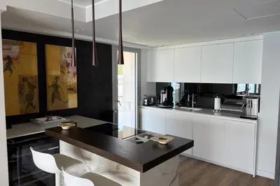 a kitchen with white cabinets and a black counter top at Superb apartment with exceptional sea view in Nice