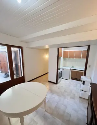 a living room with a white table and a kitchen at T2 Pasteur in Nice