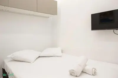 a white bedroom with a bed and a flat screen tv at WeHost D2 - Smart & chic loft, 3 mins to beaches in Nice