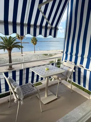 a table and chairs on a balcony with a view of the beach at Le Cormoran bord de mer in Saint-Laurent-du-Var