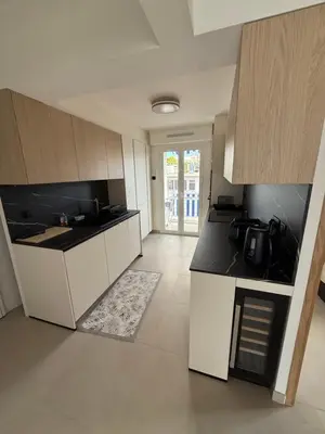 a kitchen with white cabinets and black counter tops at Le Cormoran bord de mer in Saint-Laurent-du-Var