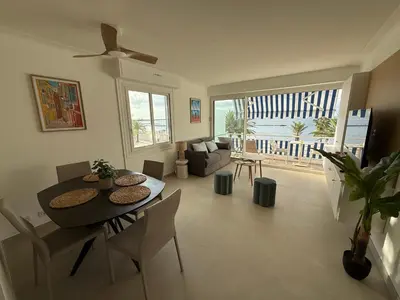 a living room with a dining room table and a couch at Le Cormoran bord de mer in Saint-Laurent-du-Var