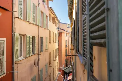 an alley between two buildings with green shutters at Nice Renting - COLLET - Cocoon Design Old Nice Beach Massena Saleya in Nice