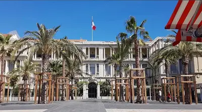 a large white building with palm trees in front of it at Central & Beach in Nice