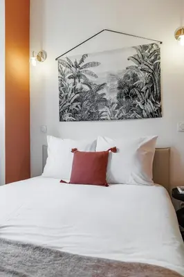 a bedroom with a white bed with a painting on the wall at 44 LAMARTINE - Charmant 2 pieces - Centre-ville in Nice
