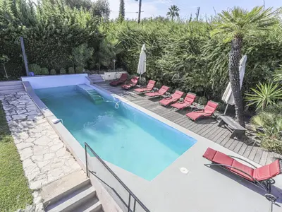 a swimming pool with chairs and umbrellas at Holiday Home Les Genêts by Interhome in Nice
