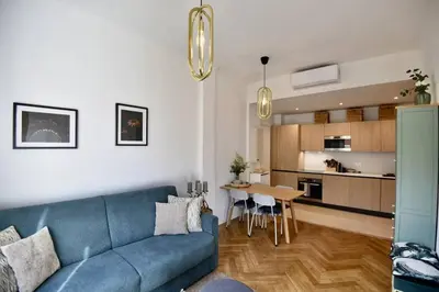 a living room with a blue couch and a kitchen at Nice Signature The Port in Nice