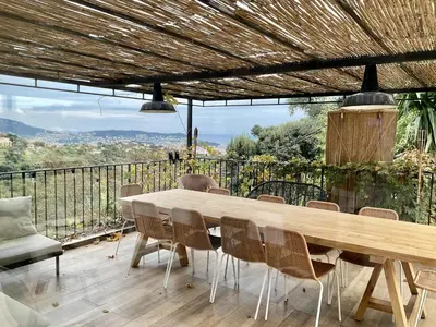 a wooden table and chairs on a deck with a view at Maison avec vue mer et jacuzzi à 15 mn du centre in Nice
