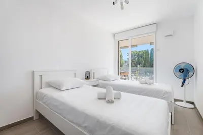 two white beds in a white room with a window at Appartement Colombier - Welkeys in Saint-Laurent-du-Var