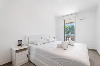 a white bedroom with a white bed and a window at Appartement Colombier - Welkeys in Saint-Laurent-du-Var
