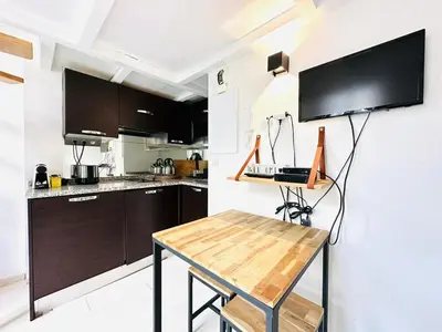 a kitchen with a table and a tv on the wall at Beautiful Carré d'Or studio in Nice