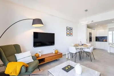 a living room with a couch a table and a tv at Appartement Prestige sur la Promenade des Anglais in Nice