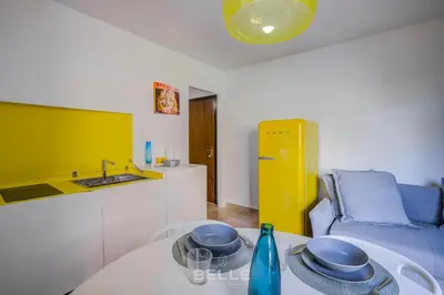 a living room with a table and a kitchen at Résidence Grand Hôtel Nice in Nice