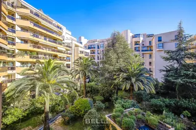 an apartment garden with palm trees in front of a building at Résidence Grand Hôtel Nice in Nice