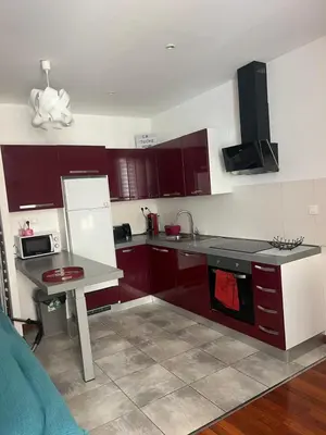 a kitchen with red cabinets and a white refrigerator at cosy appartement in Nice