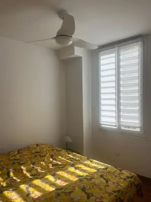 a bedroom with a bed with a yellow comforter and a window at cosy appartement in Nice