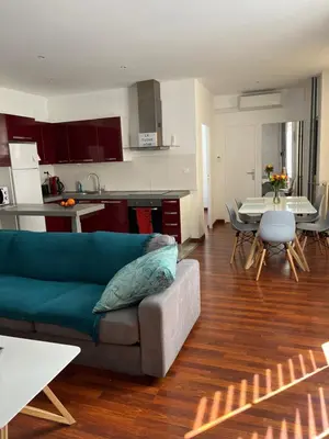 a living room with a couch and a table and a kitchen at cosy appartement in Nice