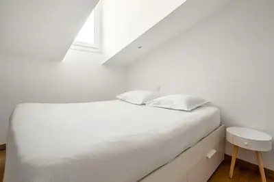 a white bed in a white room with a window at Cosy 2 pieces au Coeur du Centre Ville in Nice