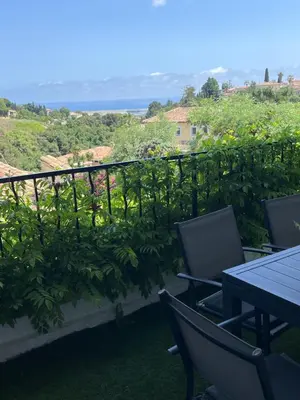 a balcony with chairs and a table and a view of the ocean at Appartement dans villa vue mer piscine partagée in Saint-Laurent-du-Var
