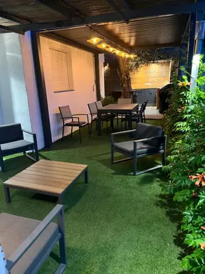 a patio with tables and chairs and green grass at Appartement dans villa vue mer piscine partagée in Saint-Laurent-du-Var