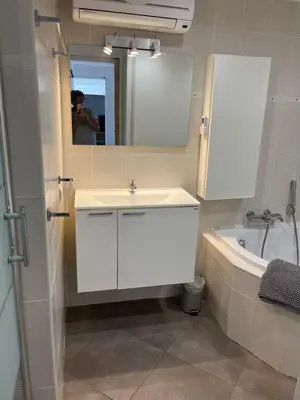 a bathroom with a sink and a tub and a mirror at Appartement dans villa vue mer piscine partagée in Saint-Laurent-du-Var