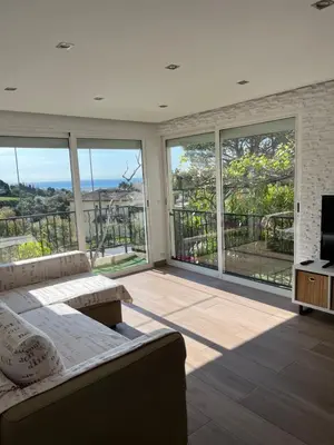 a living room with a couch and large windows at Appartement dans villa vue mer piscine partagée in Saint-Laurent-du-Var