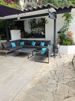 a patio with couches on a stone patio at Appartement dans villa vue mer piscine partagée in Saint-Laurent-du-Var