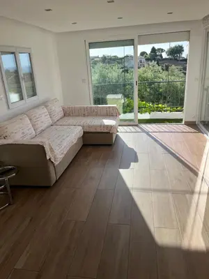 a living room with a couch and large windows at Appartement dans villa vue mer piscine partagée in Saint-Laurent-du-Var